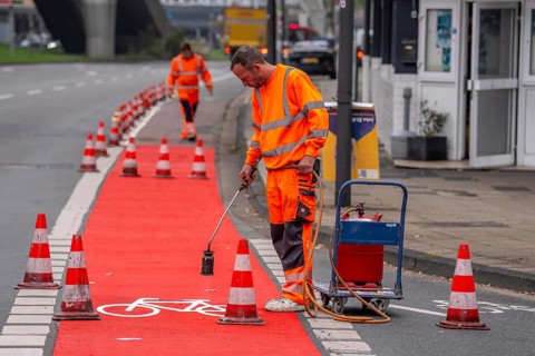 Application of red road surfacing on a cycle lane, inner-city road, so-called cold plastic