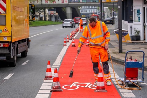 Application of red road surfacing on a cycle lane, inner-city road, so-called cold plastic