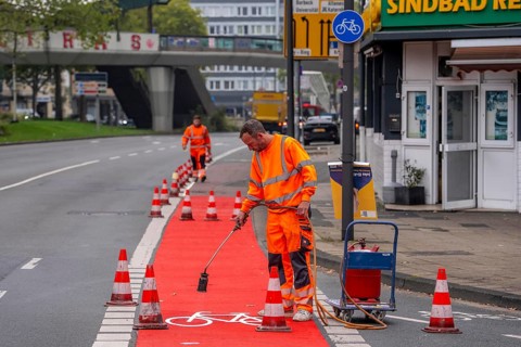 Application of red road surfacing on a cycle lane, inner-city road, so-called cold plastic