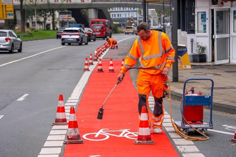 Application of red road surfacing on a cycle lane, inner-city road, so-called cold plastic