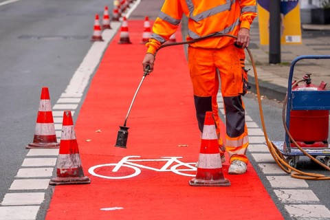 Application of red road surfacing on a cycle lane, inner-city road, so-called cold plastic