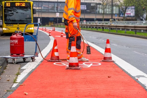 Application of red road surfacing on a cycle lane, inner-city road, so-called cold plastic