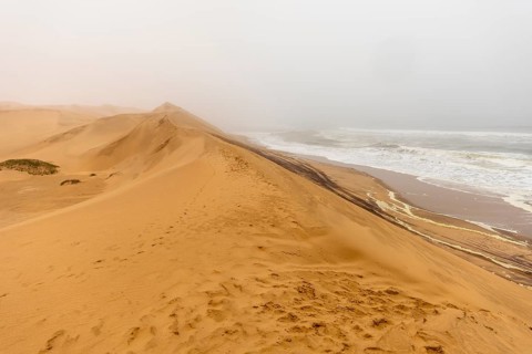 Golden dunes and the Atlantic Ocean near Namib-Naukluft Park, Namibia. A lagoon and shoreline fade