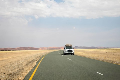 Inside Sossusvlei, gravel roads wind and a car through red dunes to Deadvlei, Big Daddy, and