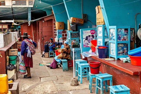 Lively street scene at a Bolivian market with people in traditional clothing and colourful chairs,