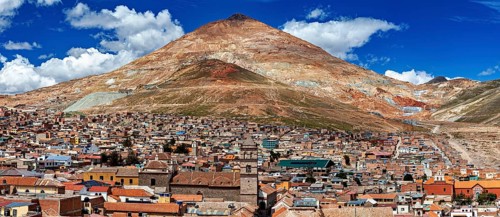 Expansive view of a city in front of an impressive mountain and blue sky, The silver mountain Cerro