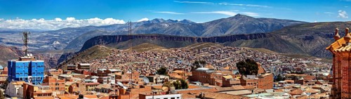 Far-reaching panorama with cityscape and surrounding mountains under a clear sky, view over the