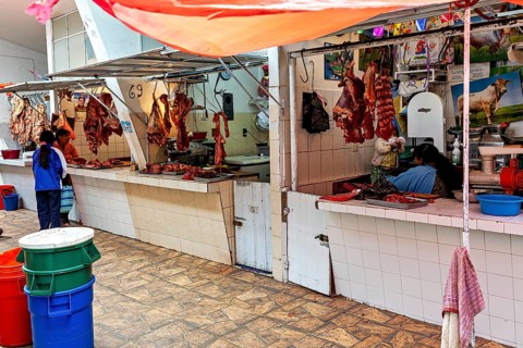 A lively meat market with customers and colourful illustrations in the background, The meat market