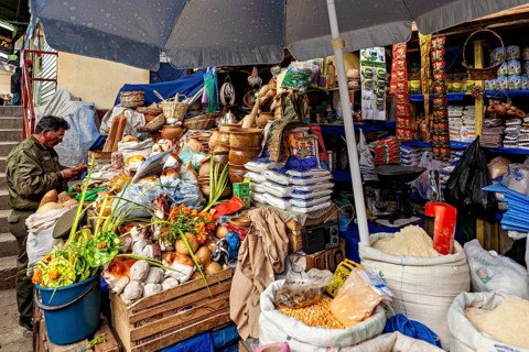 A lively market stall full of fresh vegetables, fruit and spices under a large umbrella, Extensive