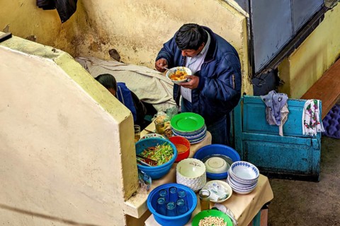 A man eats in a cosy corner with colourful crockery and a laid table, A man eats at a market stall