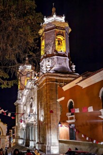 Illuminated church at night, decorated with flags and surrounded by trees, The churches of the city