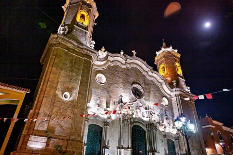 Illuminated church under the night sky with festive lights and flags, The churches of the city of