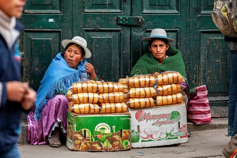 Two woman in traditional dress selling bread on the street, Bolivian Indio woman selling goods in