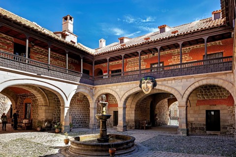 A historic courtyard with a central fountain, surrounded by colonial architecture and stone walls