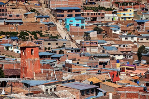 Urban area with orange-coloured roofs in a slightly hilly environment with pastel shades, view over