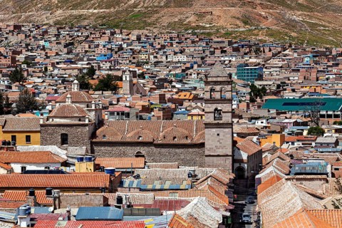Aerial view of a densely built-up city with colonial towers and colourful roofs in a mountainous