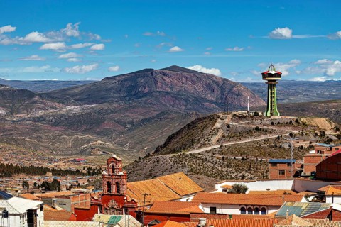 City with red roofs and observation tower, surrounded by mountains under a blue sky, The water