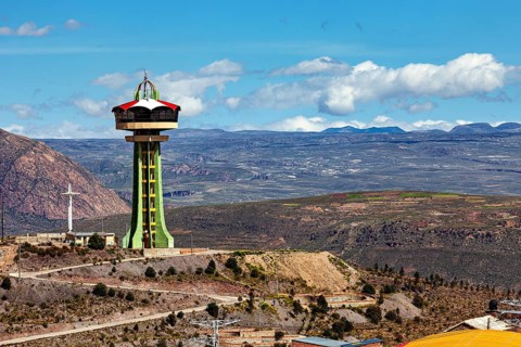 Observation tower on a hill with a cross and clouds in the blue sky in the background, The water
