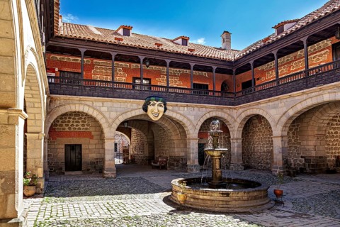 A historic courtyard with a central fountain and arches, surrounded by stone walls and colonial