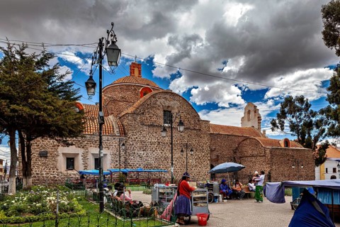 Small church with a round dome next to a busy market square under a partly cloudy blue sky, The old