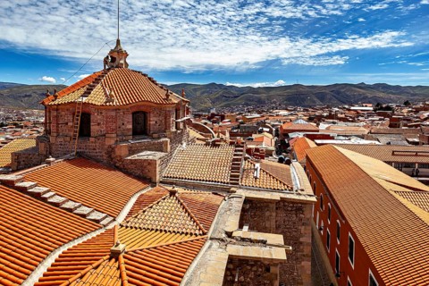 Colonial building with traditional roof tiles and mountain backdrop under a blue sky, The roof of