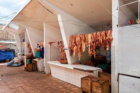 White market stall with meat hung out to dry, sunny atmosphere, rustic surroundings, The meat