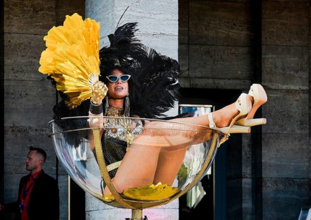 An erotic model sits in an oversized champagne glass at the Grand Opening of the Venus Erotic Fair