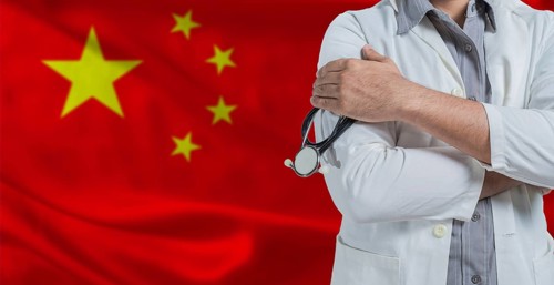 Doctor with stethoscope on arm with China flag behind. National health system of China, concept