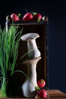 oyster mushrooms with radishes and chives in a wooden crate against a dark background