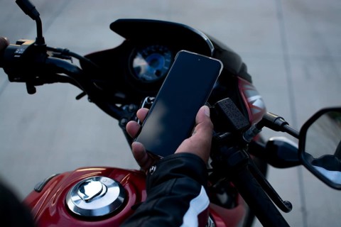 Close up of a motorcyclist holding a phone. Biker using his phone on a motorcycle