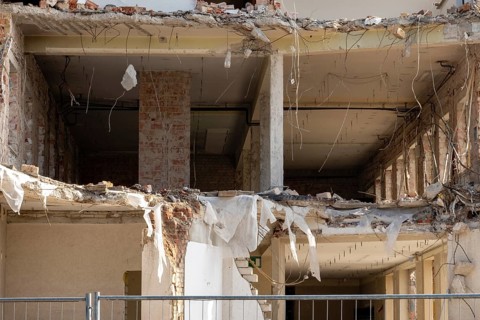 Partially demolished building showing exposed interior structure, rubble, and debris