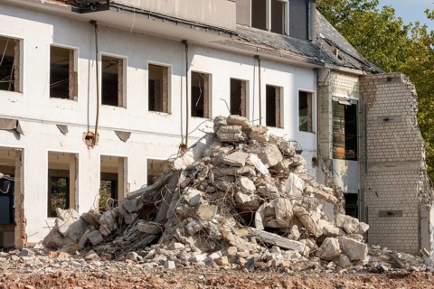 Concrete and brick rubble piling up in front of a partially demolished building