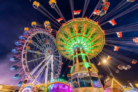 Folk festival time in Stuttgart. Ferris wheel and chain carousel in the evening. The 178th