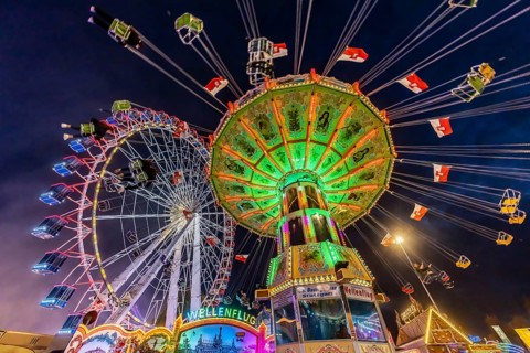 Folk festival time in Stuttgart. Ferris wheel and chain carousel in the evening. The 178th