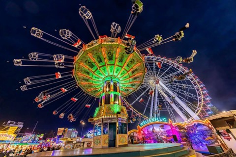 Folk festival time in Stuttgart. Ferris wheel and chain carousel in the evening. The 178th