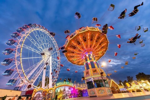 Folk festival time in Stuttgart. Ferris wheel and chain carousel in the evening. The 178th