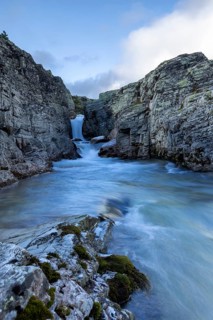 A river flows through a narrow gorge, over a small waterfall, surrounded by steep cliffs, Peer Gynt