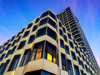 The picture shows a modern office and commercial building at the central station, warm evening