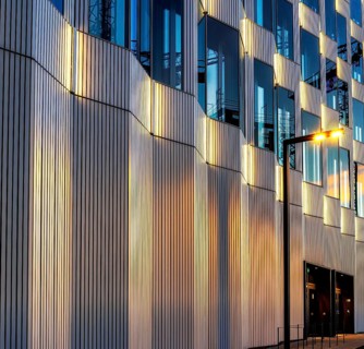 The picture shows a modern office and commercial building at the central station, warm evening