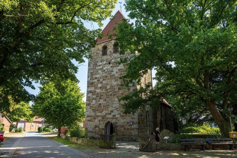 Historic stone church tower surrounded by green trees in the village, Buchholz church, Petershagen,