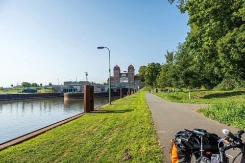 Bicycle standing on a canal path next to a lock, surrounded by green nature, Minden waterway