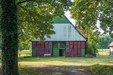 A rustic half-timbered barn with open Tor tor, surrounded by trees and nature, Gütersloh,