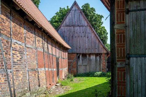 Half-timbered buildings in a green courtyard on a sunny day, Weser cycle path, Schlüsselburg barn