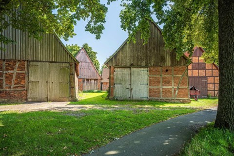 Rural path leads between old half-timbered houses surrounded by trees, Weser cycle path,
