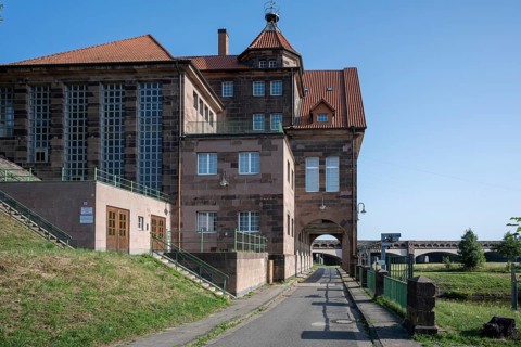 Historic building with red brick roof and large entrance gate under a blue sky, Minden waterway
