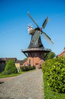 Idyllic windmill near cobbled path and gardens on a sunny day, windmill near Weener