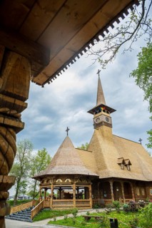 Remarkable wooden church with intricate carvings and a rustic roof against a cloudy sky, the