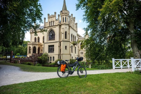 A Gothic castle with a bicycle on a path in idyllic surroundings, Evenburg Castle, Leer, East