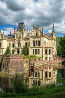 The Gothic castle with moat is picturesquely reflected in the water, Evenburg Castle, Leer, East