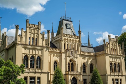 An imposing castle with Gothic elements and large windows under a blue sky, Schloss Evenburg, Leer,